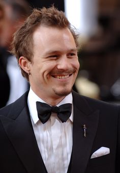 a man in a tuxedo smiles at the camera