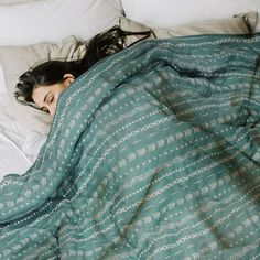 a woman laying in bed under a blanket