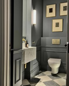 a white toilet sitting in a bathroom next to a wall mounted light above it's tank