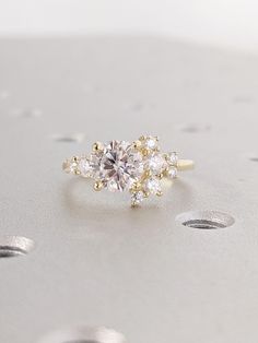 an engagement ring with three stones in the center and two diamonds on each side, sitting on top of a silver surface