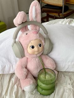 a pink stuffed animal with headphones and a drink