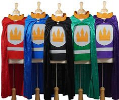 four capes with different colors and designs on them, one is wearing a crown