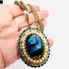 Gorgeous Vintage Signed WEST GERMANY Blue Slag Glass Faux Pearl & Rhinestone Necklace. Ornate gilt filigree metal set with blue slag glass stone and surrounded by faux pearls and blue rhinestones. Signed on jump ring. In excellent vintage condition with minimal age appropriate wear. Pendant measures 2 3/4 inches long from the heart and is 1 5/8 inches wide. Total length is 24 inches long. Clasp secure. Antique Blue Metal Jewelry, Blue Metal Cabochon Jewelry, Blue Cabochon Metal Jewelry, Blue Victorian Metal Jewelry, Blue Jeweled Metal Jewelry, Vintage Designer Jewelry, Enamel Flower, West Germany, Necklace Vintage