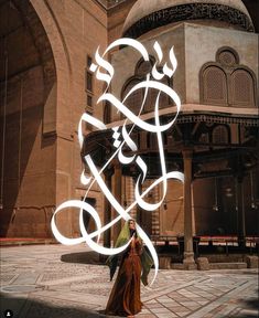 a woman walking in front of a large building with arabic writing on it's side