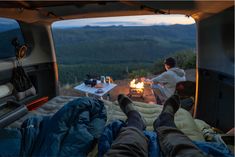 two people sitting in the back of a van with their feet up on an air mattress