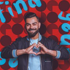 a man making a heart shape with his hands while standing in front of a colorful background