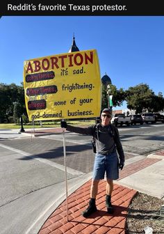 a man standing on the sidewalk holding up a sign