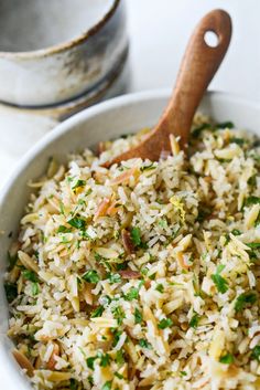 a close up of a bowl of rice with a wooden spoon in the bowl next to it