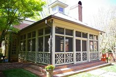 a house with screened porches and windows in the front yard on a sunny day