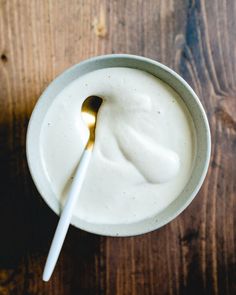 a spoon in a bowl filled with yogurt on top of a wooden table