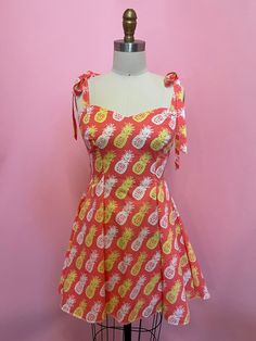 a mannequin wearing a red and yellow dress with pineapples on it