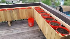 several red buckets filled with dirt on top of a wooden deck