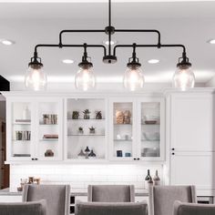 a kitchen with white cabinets and gray chairs