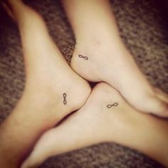 two people with matching tattoos on their feet are laying in the middle of each other