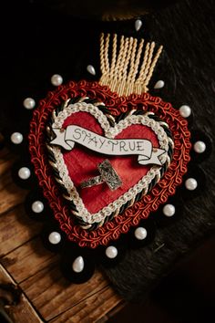 a red heart with a cross on it and some pins in the shape of a house