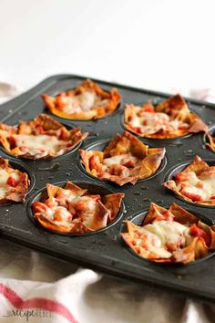 mini pizzas sitting in muffin tins on top of a table