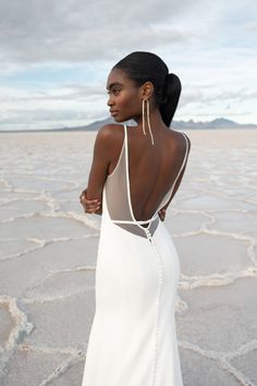 a woman in a white dress standing on the desert