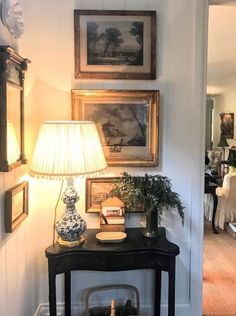 an instagram photo of a living room with pictures on the wall and a lamp