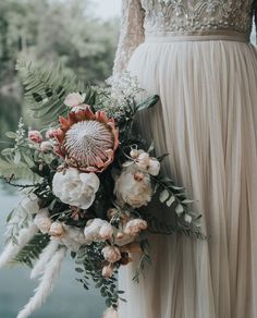 the bride is holding her bouquet by the water