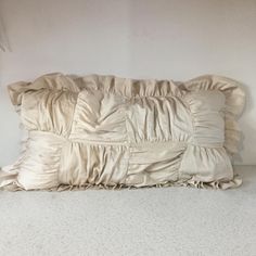 a white pillow sitting on top of a bed next to a wall with a window