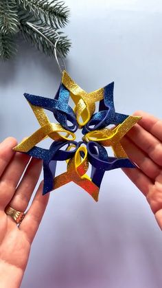 someone is holding up a star ornament with ribbons on it's side