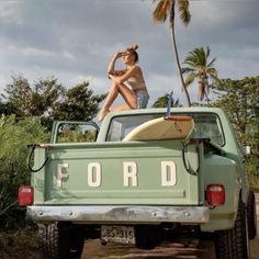 a woman sitting on the back of a green truck