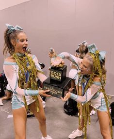 two cheerleaders are performing in front of a trophy with their hands on each other's hips