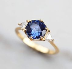 a blue and white diamond ring with three diamonds on the side, set in yellow gold