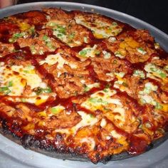 a large pizza sitting on top of a pan covered in sauce and toppings,