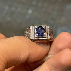 a person holding a ring with a blue stone in it's center and diamond accents around the band