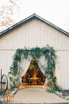 an outdoor wedding venue with greenery and white draping on the front door