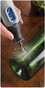 a person using a bottle opener to open a wine bottle on a wooden table next to a potted plant