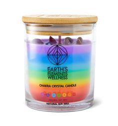 a candle that is inside of a glass jar with rocks in the center and rainbow colors on