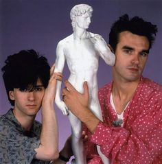 two young men are posing with a white statue in front of them, one is holding his arm up to the other's head