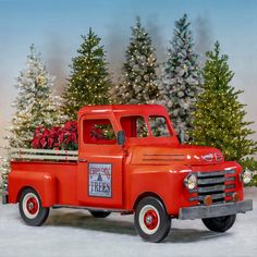 an old red truck with christmas trees in the back