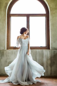 a woman standing in front of a window wearing a dress