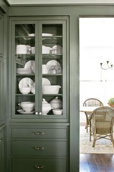 a green china cabinet with dishes in it