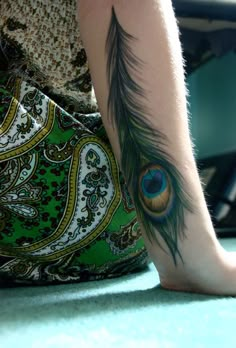 a woman's leg with a peacock feather tattoo on her left arm and foot