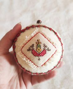 a hand holding a small embroidered ornament