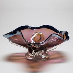 a pink glass bowl sitting on top of a white table next to a silver object