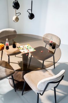 a glass table with chairs and bottles on it