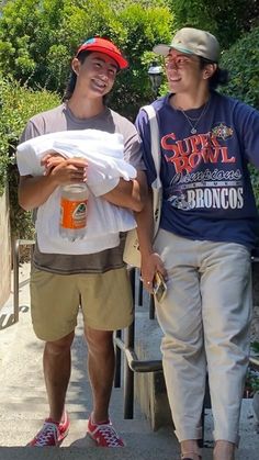 two young men walking down a sidewalk carrying bags