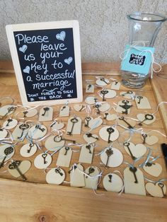 a wooden table topped with lots of key shaped magnets and a sign that says please leave us your hey to a successful marriage