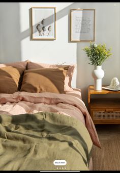 a bed with two pictures on the wall above it and a plant in a vase