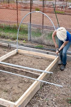 a man is working on building a raised garden bed in the yard with steel bars