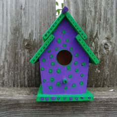 a purple birdhouse sitting on top of a wooden fence