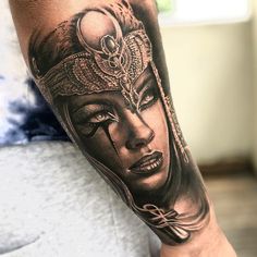 a woman's face with an elaborate headpiece on her arm, done in black and grey