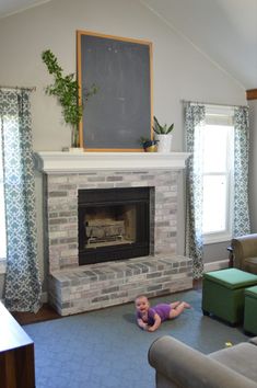 a baby laying on the floor in front of a fireplace