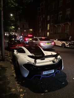 a white sports car parked on the side of a road at night with police cars behind it