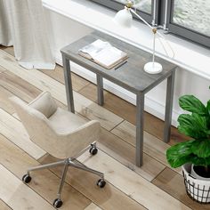 a desk with a chair, lamp and potted plant in front of the window